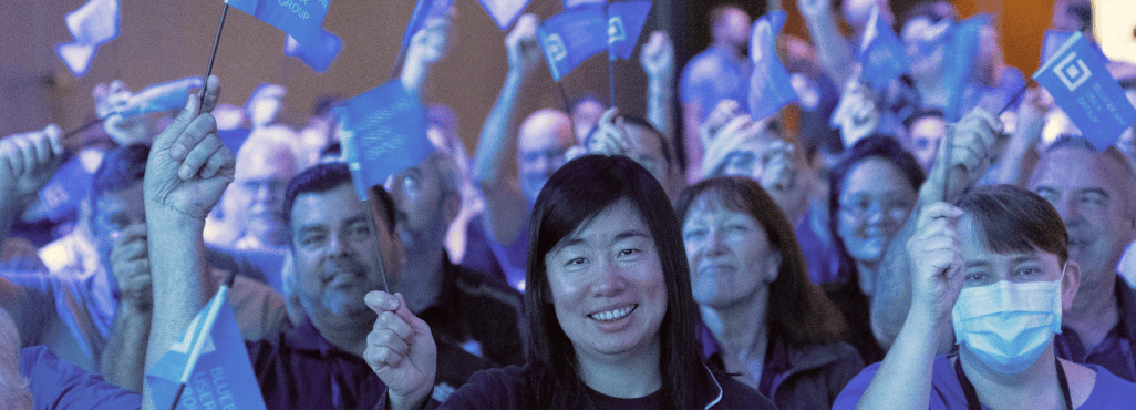 People smiling at the camera holding flags