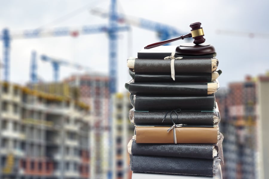Gavel on a pile of books with construction site in the background