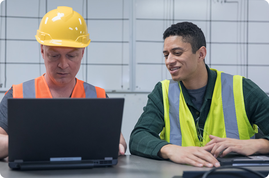 Two construction workers looking at a laptop together