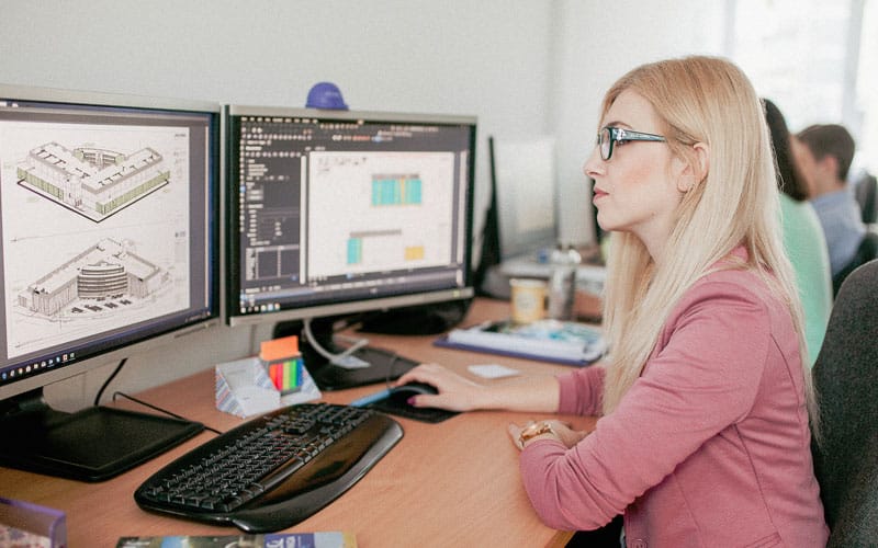 kvinna på kontor arbetar med byggfiler på en dator
